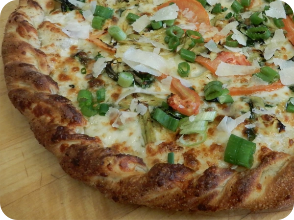 Fresh baked pizza with green onions and tomatoes